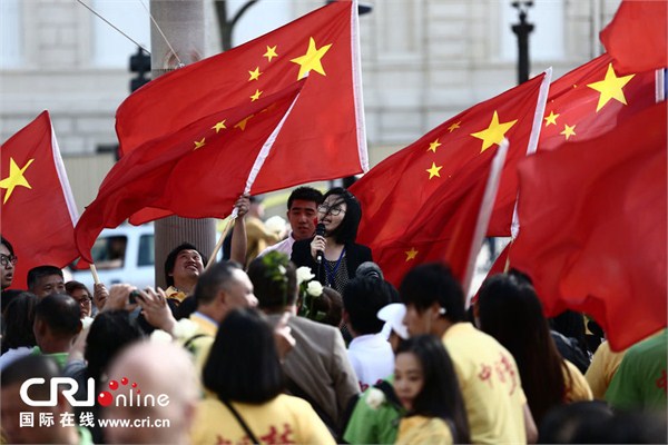 当地时间2014年6月15日，法国巴黎，香榭丽舍大街上红旗飘飘。华人共进会的发言人正在集会现场发表小型演讲，该协会是本次活动的主要组织者。