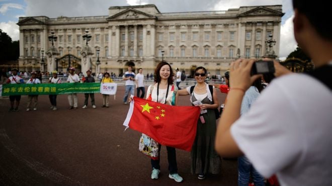 《经济学人》智库文章预测，未来15年中国高收入消费群体将成倍增加，在旅游等方面花销更多。图为2012年7月，伦敦白金汉宫门前的中国游客。