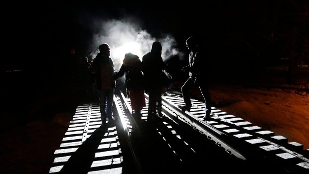 Asylum seekers move carefully along a railway overpass in Emerson, Man. earlier in March.