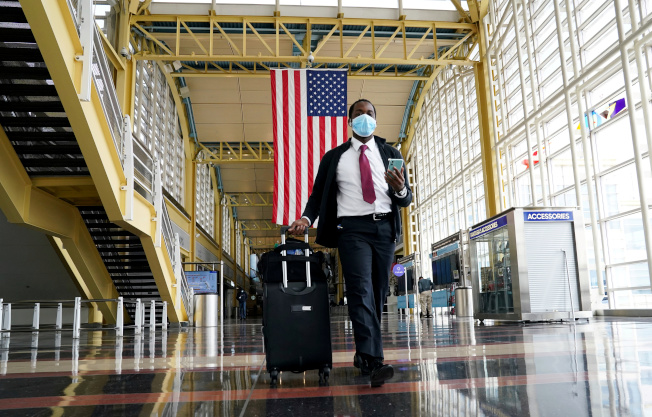 全美16州新冠确诊人数仍在增加。图为游客走出华府雷根机场。(路透)