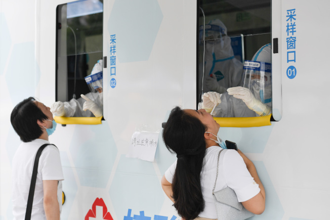图为北京市西城区一处露天广场上，核酸检测采样车内的医护人员正民众进行采样。（新华社）