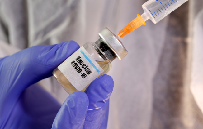 马里兰州生技制药业者Novavax公司规模不大，却获得来自联邦卫生福利部、国防部共计16亿元资金，协助研发并制造能够对抗新冠病毒的疫苗。图为一妇女拿着“新冠病毒”标签的试剂瓶。(路透)