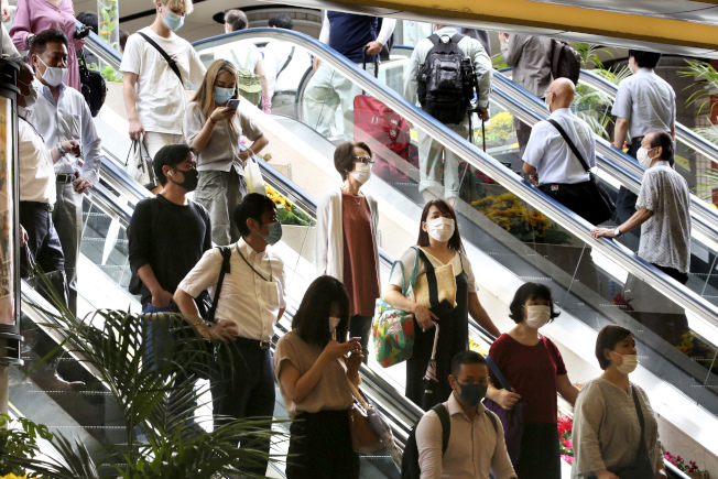 图为在日本东京附近的横滨站，民众戴上口罩搭乘手扶电梯。美联社