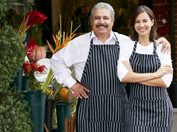 Portrait Of Male And Female Florist Outside Shop, man has arm around young woman