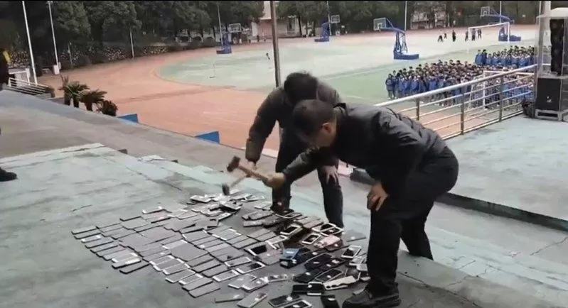 湖南一学校当众砸毁没收学生的上百部手机 网怒：带头违法