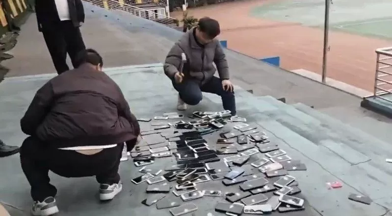 湖南一学校当众砸毁没收学生的上百部手机 网怒：带头违法