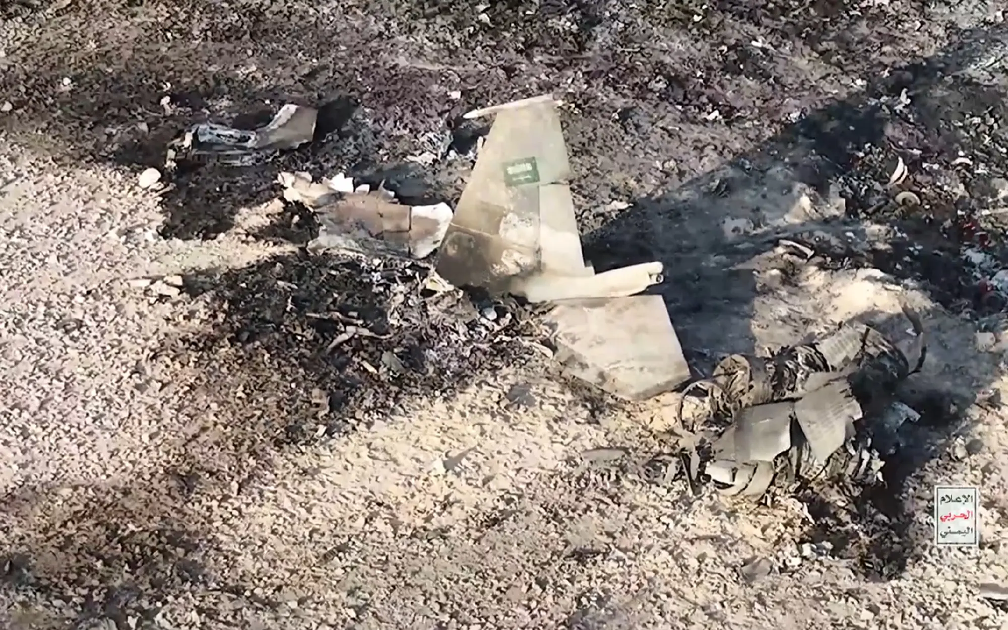 踩在F-15残骸上，胡塞武装举枪庆祝，巨大垂尾上的沙特国旗很扎眼