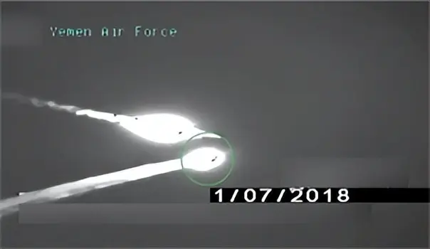 踩在F-15残骸上，胡塞武装举枪庆祝，巨大垂尾上的沙特国旗很扎眼
